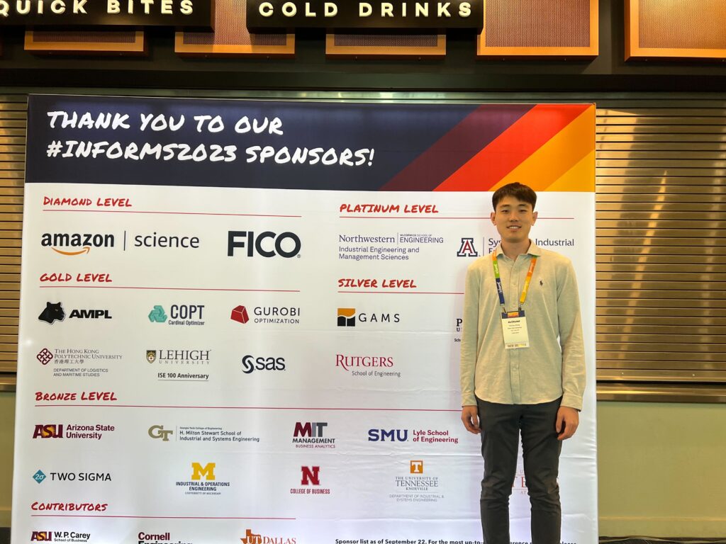Ruixuan in front of INFORMS 2023 sponsor backdrop