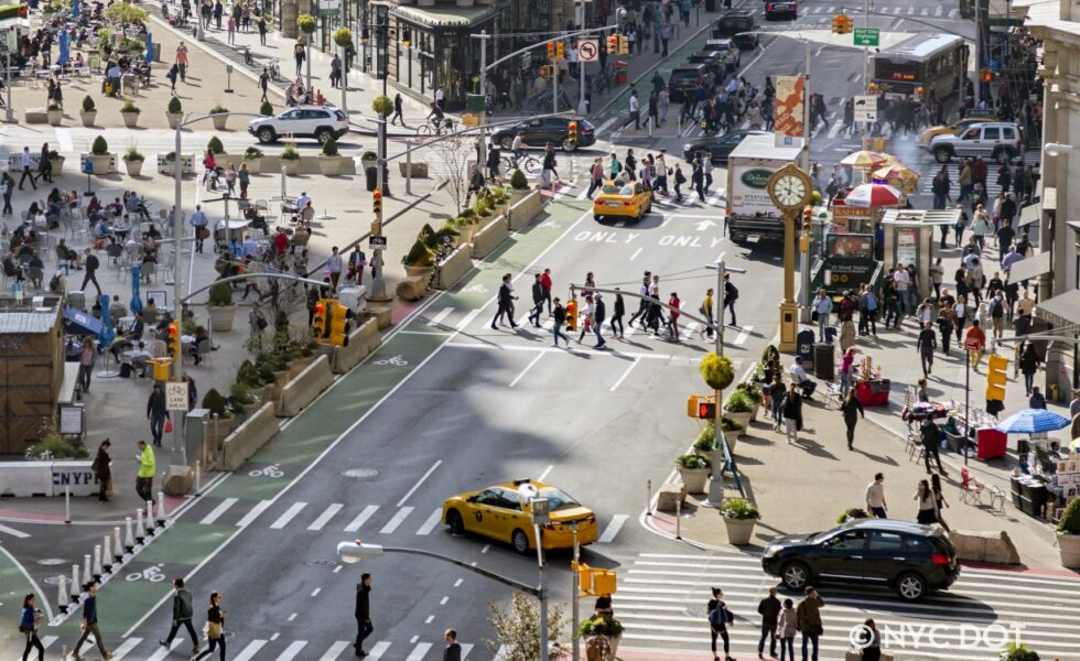 photo of people and cars crossing Flatiron Plaza, 23rd Street and 5th Avenue, in Midtown, Manhattan